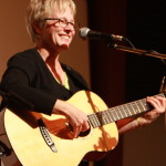 photo of Tracy Newman standing on stage with acoustic guitar at Folktacular 2008