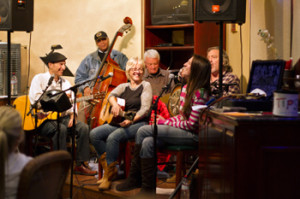 group photo of Tracy Newman and her five band members, The Reinforcements, seated together on stage